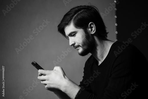 Black and white portrait of young man with smartphone in hand.