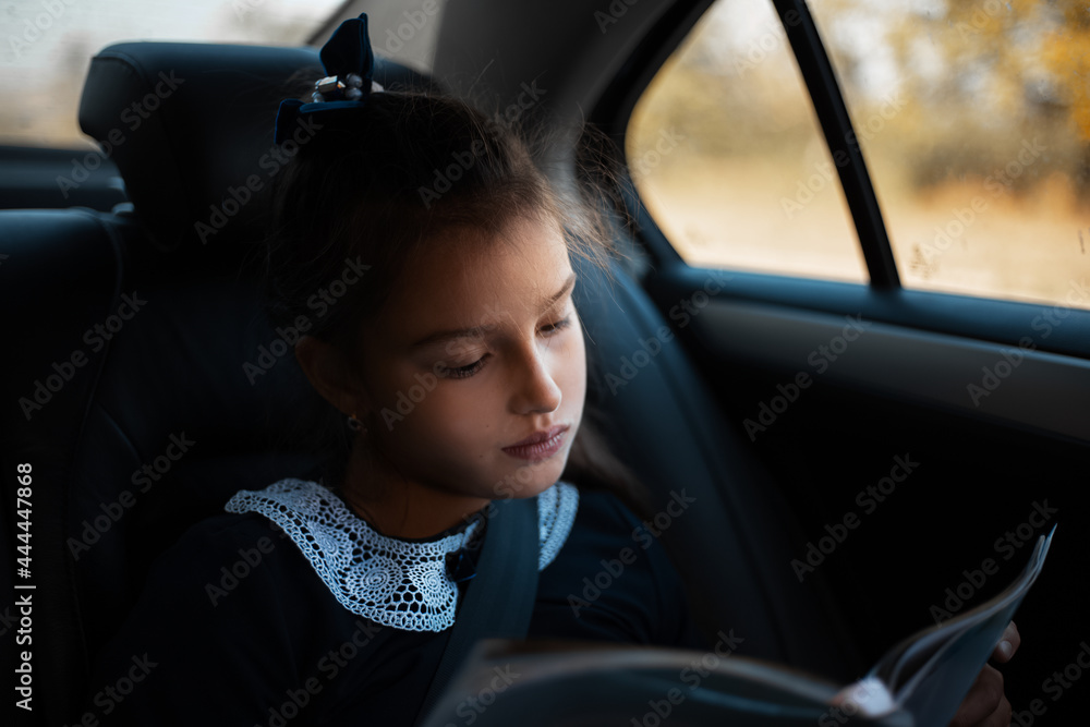 Child girl reading a book inside car in traffic time.