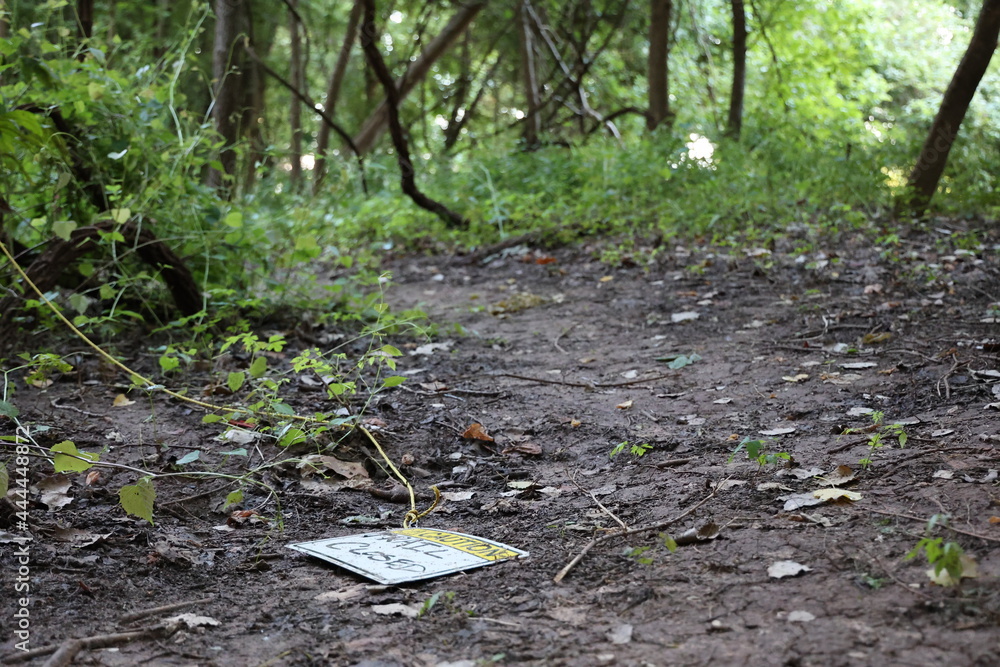 Obraz premium Warning sign knocked down on muddy dirt trail