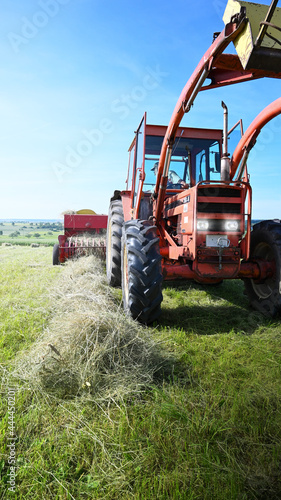 Old tractor with hay baler pressing summer hay. © JOE LORENZ DESIGN