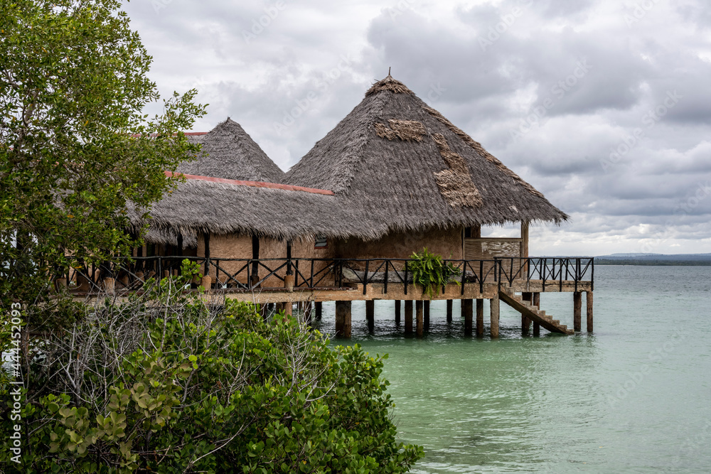 landscape of an island in the sea with trees, thatched roof buildings and resting places landscape of an island in the sea with trees, thatched roof buildings and resting places