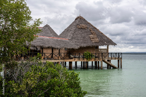 landscape of an island in the sea with trees, thatched roof buildings and resting places 