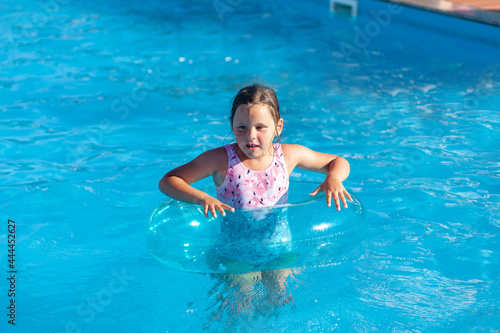 happy girl in an inflatable circle for protection in the water learn to swim in the hotel pool  rest and weekend activity. 