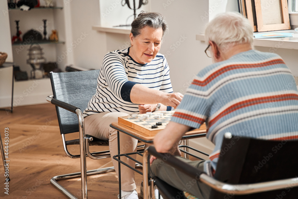 Checkers tournament between senior loving couple at the retirement house Checkers tournament between senior loving couple at the retirement house