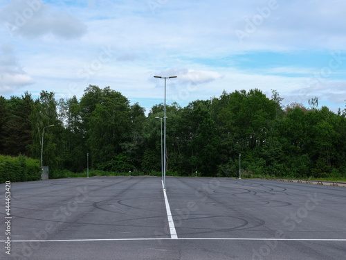 Empty car park with skid marks. Woodland background.