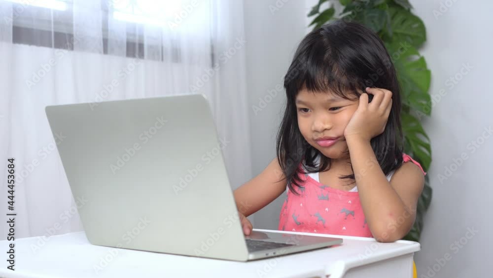 Funny Asian child learning class study online with a video calls from a notebook with a teacher at home and was sleepy and fell asleep, Concept of online education and homeschool Funny Asian child learning class study online with a video calls from a notebook with a teacher at home and was sleepy and fell asleep, Concept of online education and homeschool