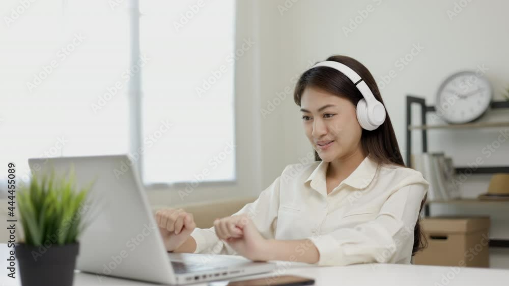 Young beautiful asian business woman finish working and celebrate with two hand stretch. Women finished work and rest She works at home in the living room listen to music with headphone. Young beautiful asian business woman finish working and celebrate with two hand stretch. Women finished work and rest She works at home in the living room listen to music with headphone.