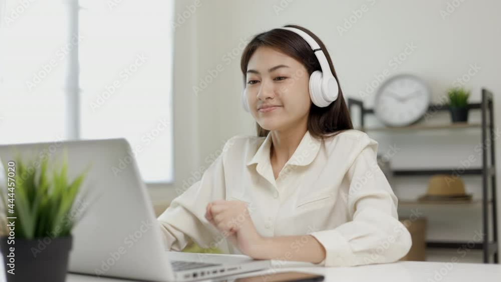Young beautiful asian business woman finish working and celebrate with two hand stretch. Women finished work and rest She works at home in the living room listen to music with headphone. Young beautiful asian business woman finish working and celebrate with two hand stretch. Women finished work and rest She works at home in the living room listen to music with headphone.