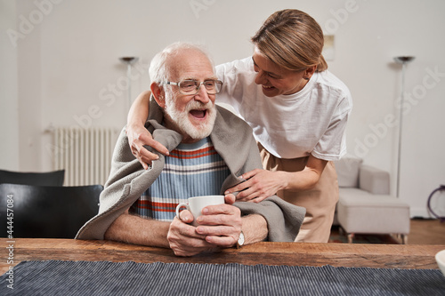 Murse warming up with blanket her senior patient while working photo