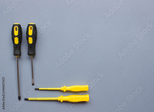 top view of set of black and yellow srewdrivers on blue grey background. Repairing tools. Free copy space photo