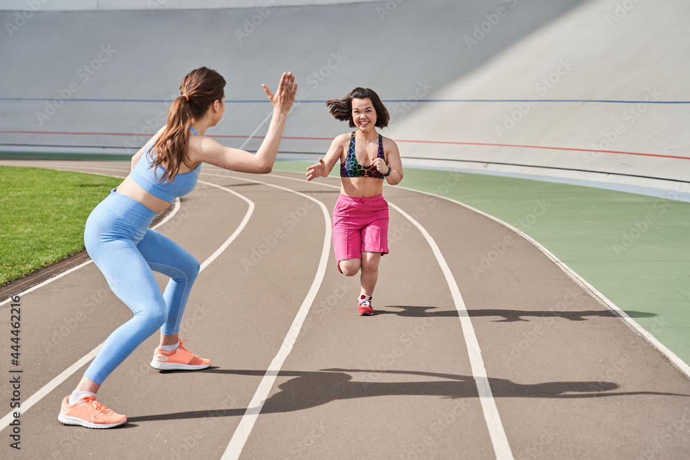 Girl waiting at the finish and giving five to her midget friend while she running Girl waiting at the finish and giving five to her midget friend while she running