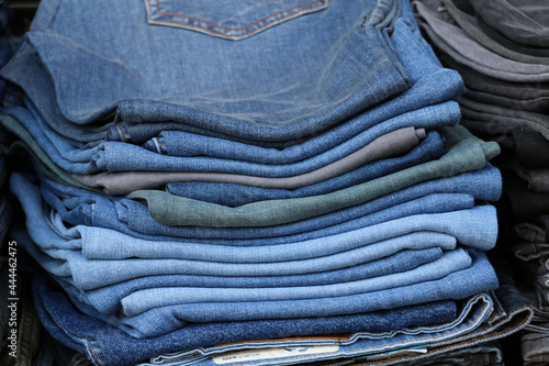 selective focus, pile of folded jeans on shelf. Jeans portrait in different colors