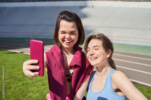 Girls looking at the smartphone camera and squinting of the sun photo