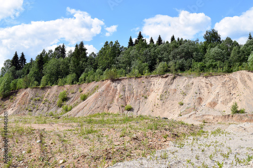 Sandy hills of the quarry, blue sky and trees. Summer sunny landscape.