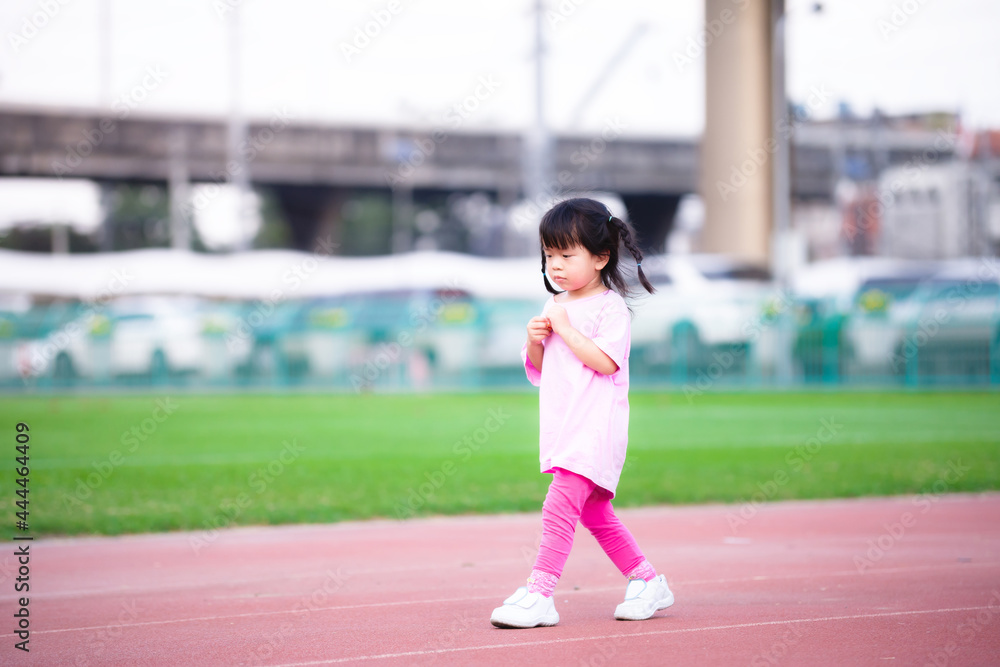 Cute Asian girl showing insecure or embarrassed expression. Children walking on the playground. Kid aged 4-5 years old. Child wear pink t-shirts.