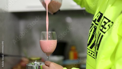 mujer se sirve un refrescante jugo de fresa en una copa de vidrio photo