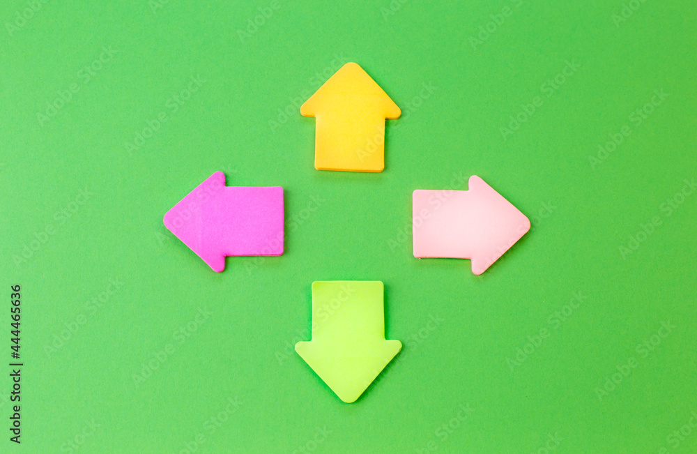 Green background with colorful arrow signs. The concept of choosing a path or direction. Green background with colorful arrow signs. The concept of choosing a path or direction.