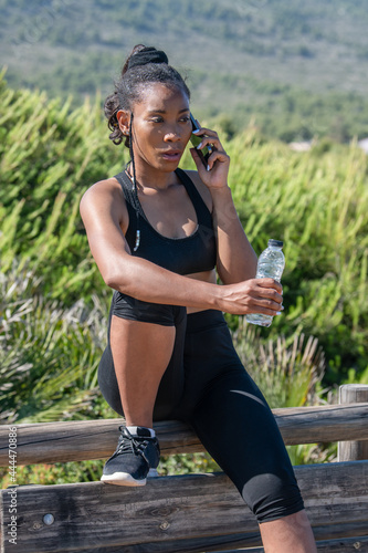 Fototapeta Naklejka Na Ścianę i Meble -  Concerned afro american woman talking on her phone on a break after exercising