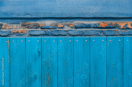 Vintage wood background with peeling paint and row of dilapidated bricks. Old wall textures closeup. Shabby wooden planks with knots and nailheads photo