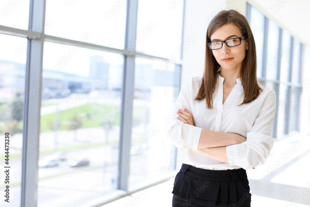 Beautiful female specialist with dark hair standing in modern office and smiling charmingly. Working on design, data analysis, plan strategy. Business people concept Beautiful female specialist with dark hair standing in modern office and smiling charmingly. Working on design, data analysis, plan strategy. Business people concept