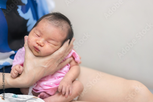 Asian mother hold tiny newborn baby with hand for help infant belch after breastfeeding milk to heal gas pain or indigestion, Health care newborn at home. photo