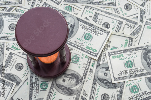 One hundred US dollars banknotes  with hourglass sand clock. Cash one hundred dollar bills, 100 dollars, Benjamin Franklin portrait, american currency exchange finance.