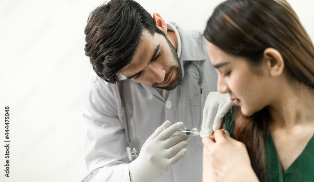 Male doctor with syringe doing injection of vaccine to female patient. Male doctor with syringe doing injection of vaccine to female patient.