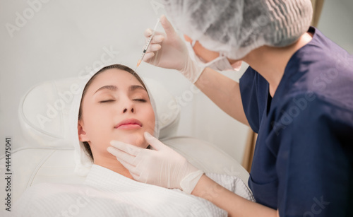 Beauty clinic concept. Asian woman lying on bed and cosmetologist does injections to face augmentation for anti wrinkle in beauty clinic.