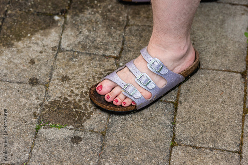 Red painted toe nails on a foot in a purple sandal.