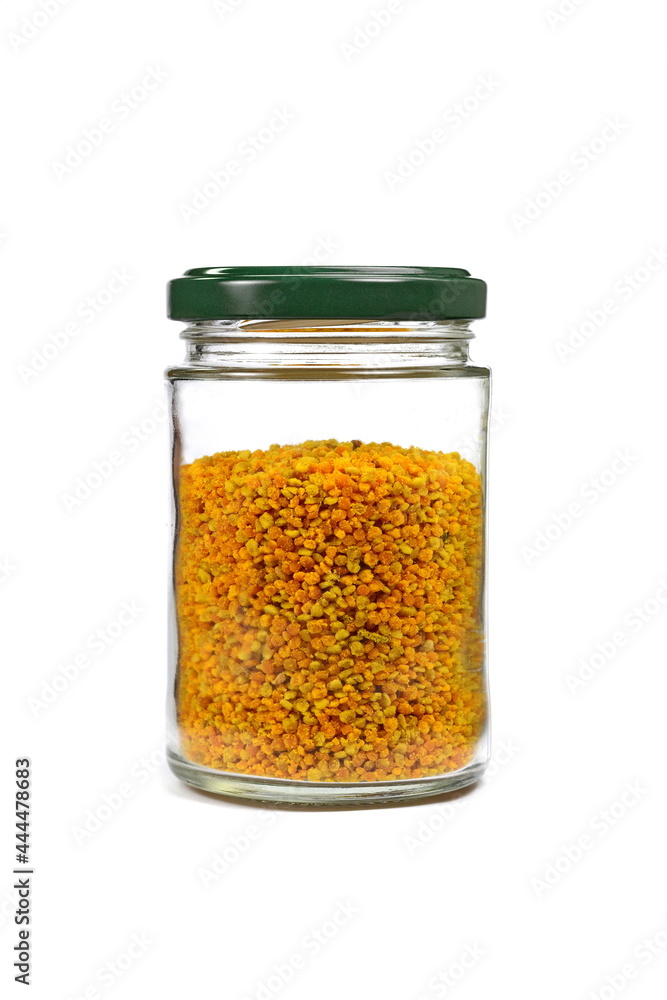 bee pollen in a transparent glass jar spilled on a white background bee pollen in a transparent glass jar spilled on a white background