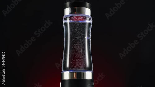 Portable device for ionization, structuring, enrichment of water alkalinity. On a red background, a dark background. for drinking water. photo