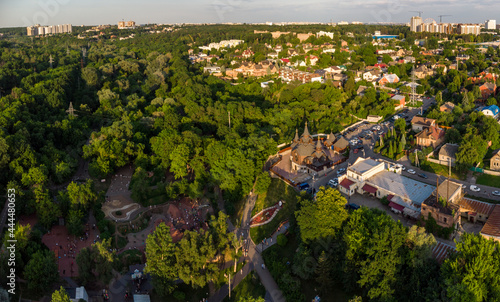 Aerial evening view on playground and church in green summer Kharkiv city center popular recreation park Sarzhyn Yar. Botanical garden in residential area in sunset light