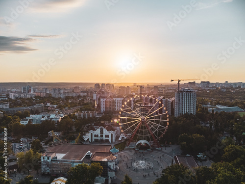 Ferris wheel spinning aerial sunset view in Kharkiv city center, amusement Park of Maxim Gorky. High attraction for recreation and city observation in residential area