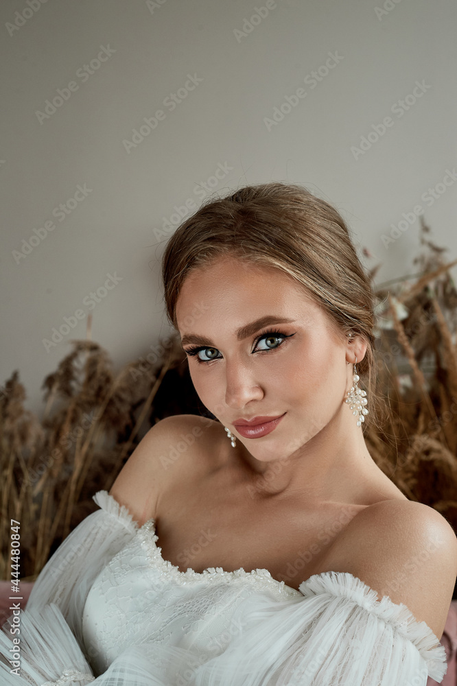 Portrait of the bride in a white dress with open shoulders. Tanned skin. Professional makeup. Portrait of the bride in a white dress with open shoulders. Tanned skin. Professional makeup.