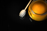 fresh honey in a jar and a honey spoon on a black background. High quality photo