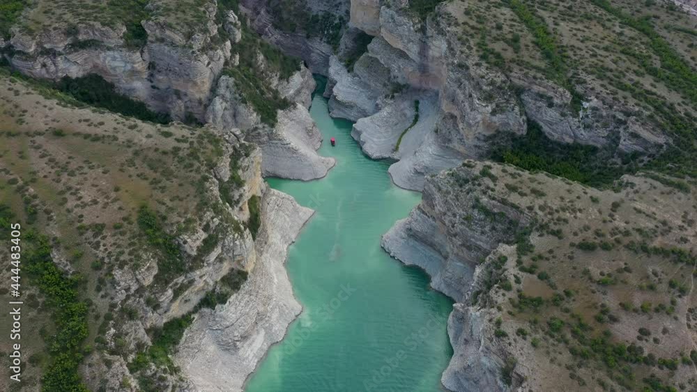 Top view of a mountain river in the canyon and a passenger boat sailing along a turquoise river among the rocks. Drone clip of the beautiful blue river and speed boat Top view of a mountain river in the canyon and a passenger boat sailing along a turquoise river among the rocks. Drone clip of the beautiful blue river and speed boat