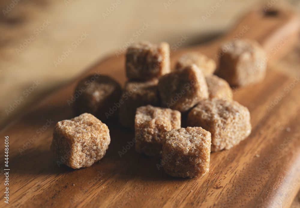 A brown cane sugar cube on a wooden cutting board. A brown cane sugar cube on a wooden cutting board.