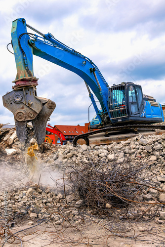Demolition excavator separating irons and concrete on construction site - Abbruchbagger trennt Eisen und Beton auf Baustelle