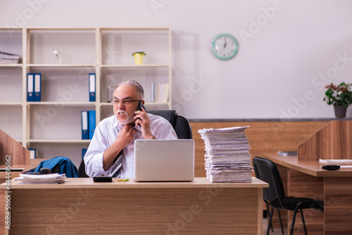 Old male employee unhappy with excessive work in the office © Elnur