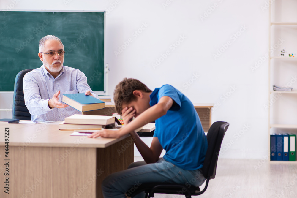 Old male teacher and schoolboy in the classroom