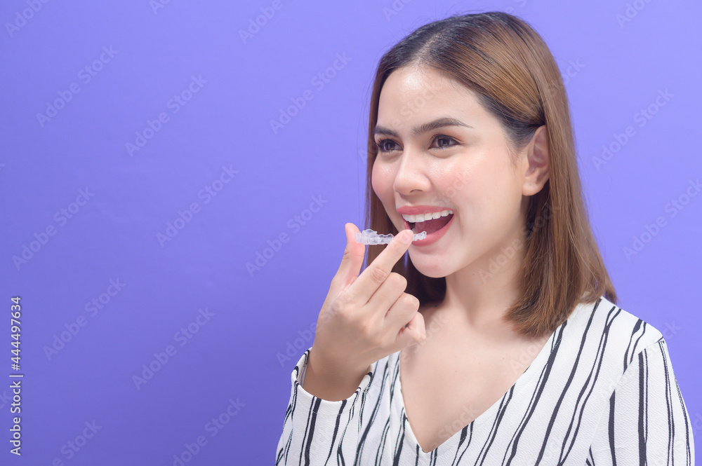 Young smiling woman holding invisalign braces in studio, dental healthcare and Orthodontic concept.. Young smiling woman holding invisalign braces in studio, dental healthcare and Orthodontic concept..