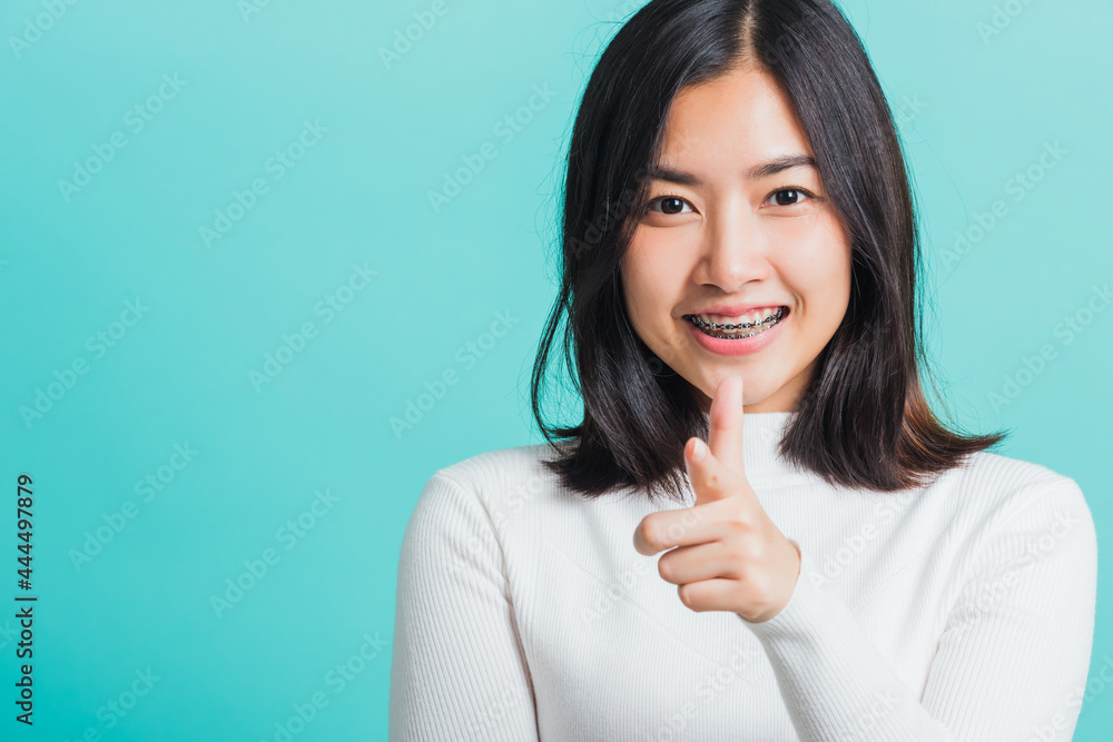 Young beautiful Asian woman smiling point finger at you with a confident expression, Portrait female pointing finger gesture towards you, studio shot isolated on a blue background Young beautiful Asian woman smiling point finger at you with a confident expression, Portrait female pointing finger gesture towards you, studio shot isolated on a blue background