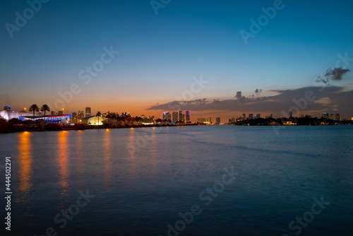 Miami, Florida cityscape skyline on Biscayne Bay. Panorama at dusk with urban skyscrapers and bridge over sea with reflection.