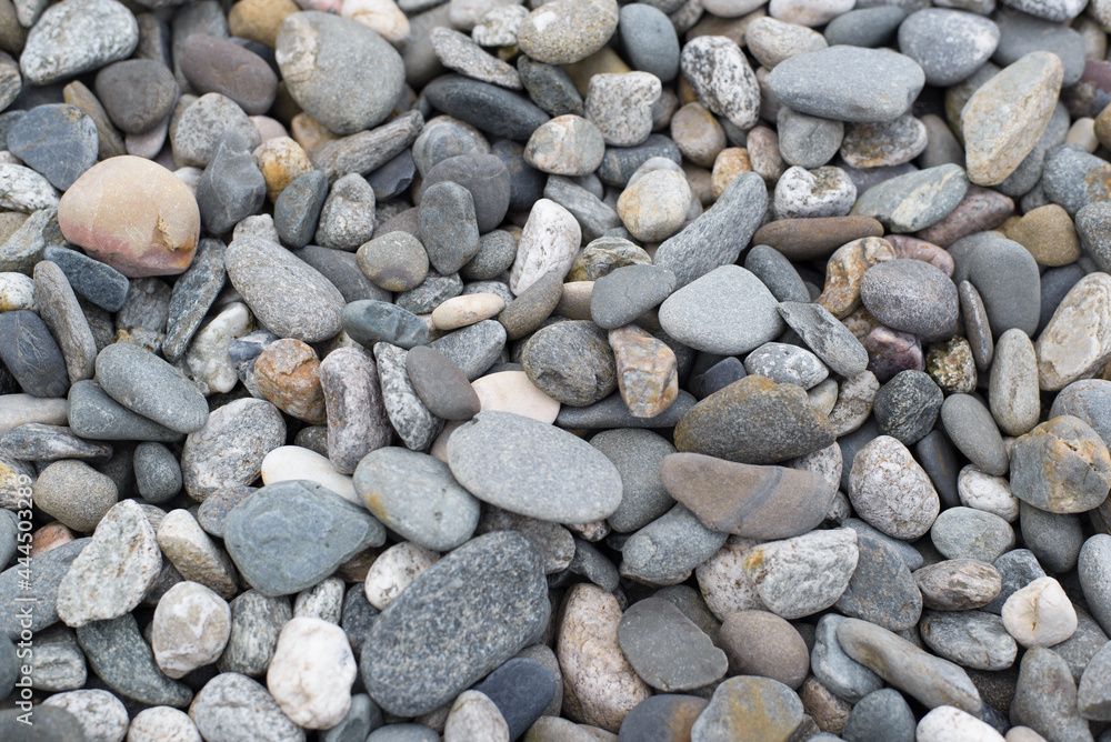 Flat pebble texture natural stone background, top view. Flat stones of various colors and sizes, used in garden or beach decoration Flat pebble texture natural stone background, top view. Flat stones of various colors and sizes, used in garden or beach decoration