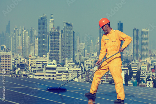 A man cleaning of solar panel .the concept of working in solar energy station on the city town.