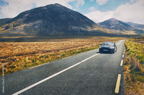 Obraz na płótnie Beautiful landscape scenery with car driving on the empty road with mountains in the background at Connemara National park in county Galway, Ireland w salonie