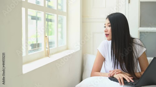 woman wearing t-shirt sitting in bed looking at the cellphone video call to her friend,social network comunication concept