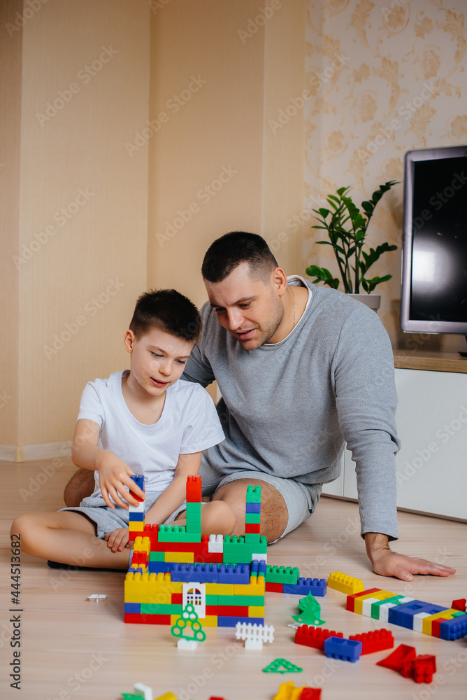 A little boy together with his father is played by a constructor and builds a house. Construction of a family home. A little boy together with his father is played by a constructor and builds a house. Construction of a family home.
