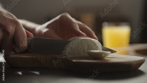 man slicing mozzarella on olive wood board