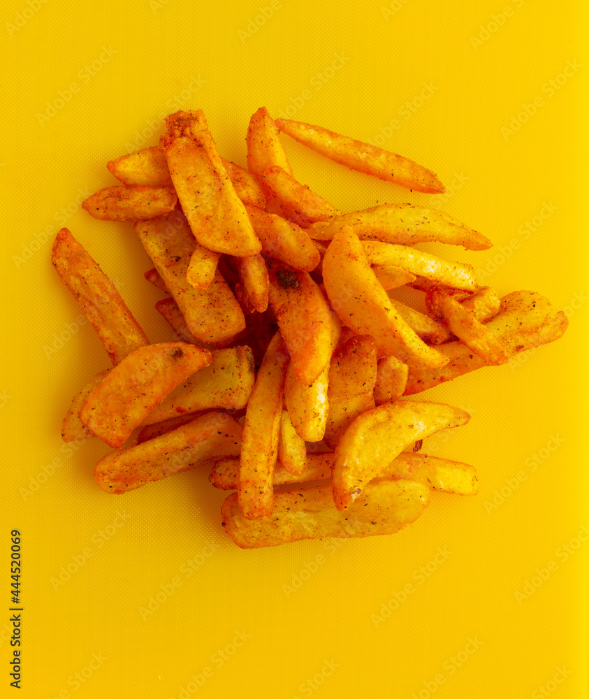 Heap of french potatoes with spices on a yellow background Heap of french potatoes with spices on a yellow background